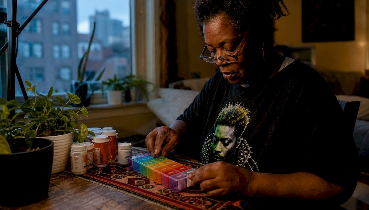 Person organizing weekly pillbox at home