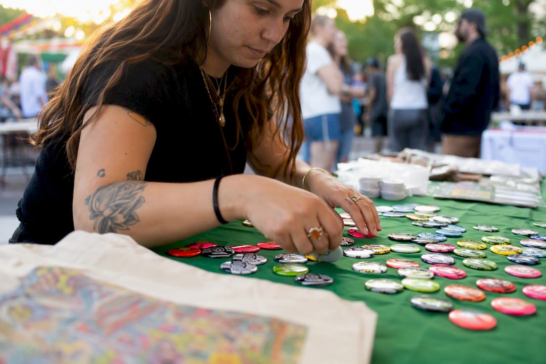 Volunteer arranging enamel buttons on event table