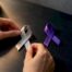 Hands choosing silver over purple awareness ribbons