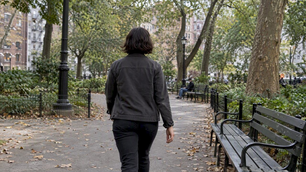 Woman walking through a leafy city park